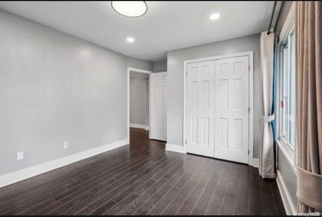 unfurnished bedroom with a closet and dark hardwood / wood-style floors