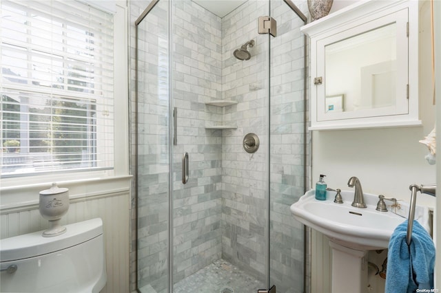 bathroom with sink, a shower with door, and toilet