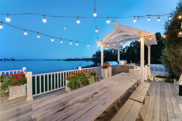 wooden terrace with a pergola, a grill, a water view, and exterior kitchen