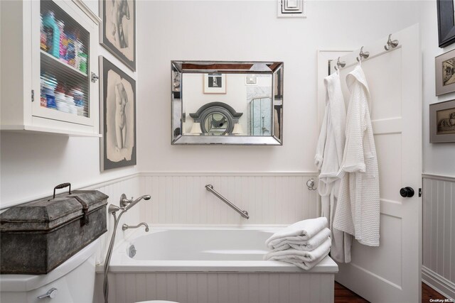 bathroom featuring a washtub, hardwood / wood-style flooring, and toilet