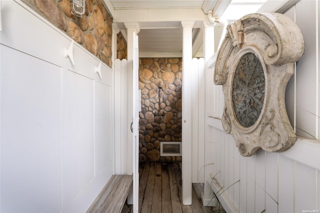 interior space featuring wood-type flooring, ornate columns, and wooden walls