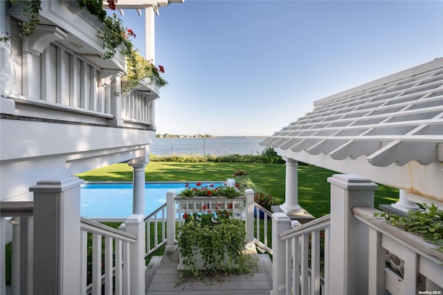 wooden deck with a water view and a lawn