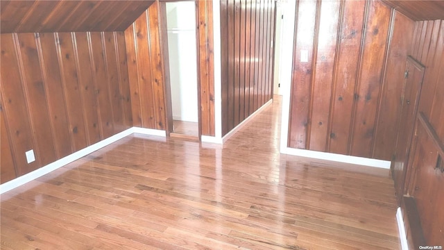 bonus room featuring light hardwood / wood-style floors, vaulted ceiling, and wood walls