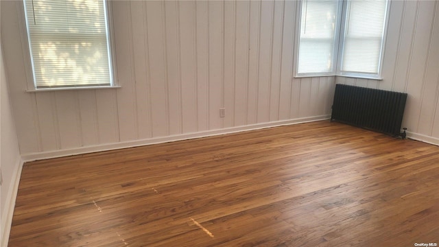 empty room with radiator, wooden walls, and hardwood / wood-style flooring