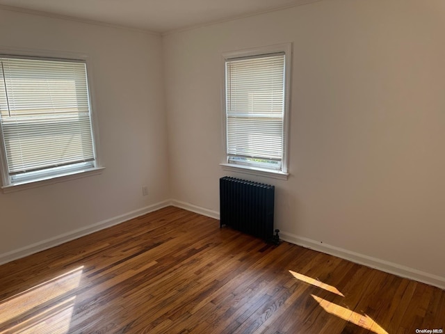 empty room with dark hardwood / wood-style flooring and radiator heating unit