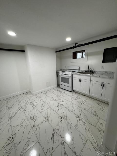 kitchen featuring white cabinetry, sink, and white range