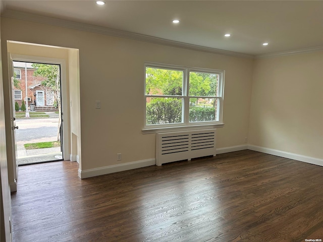 spare room featuring dark wood-type flooring, radiator, and a healthy amount of sunlight