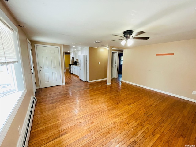 unfurnished room with ceiling fan, a healthy amount of sunlight, a baseboard radiator, and light hardwood / wood-style flooring