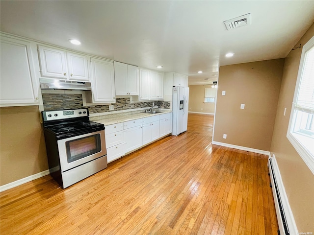 kitchen with white refrigerator with ice dispenser, stainless steel range with electric cooktop, light wood-type flooring, baseboard heating, and white cabinetry