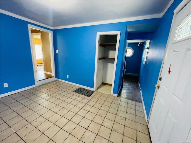 unfurnished bedroom featuring a closet, light tile patterned flooring, and ornamental molding