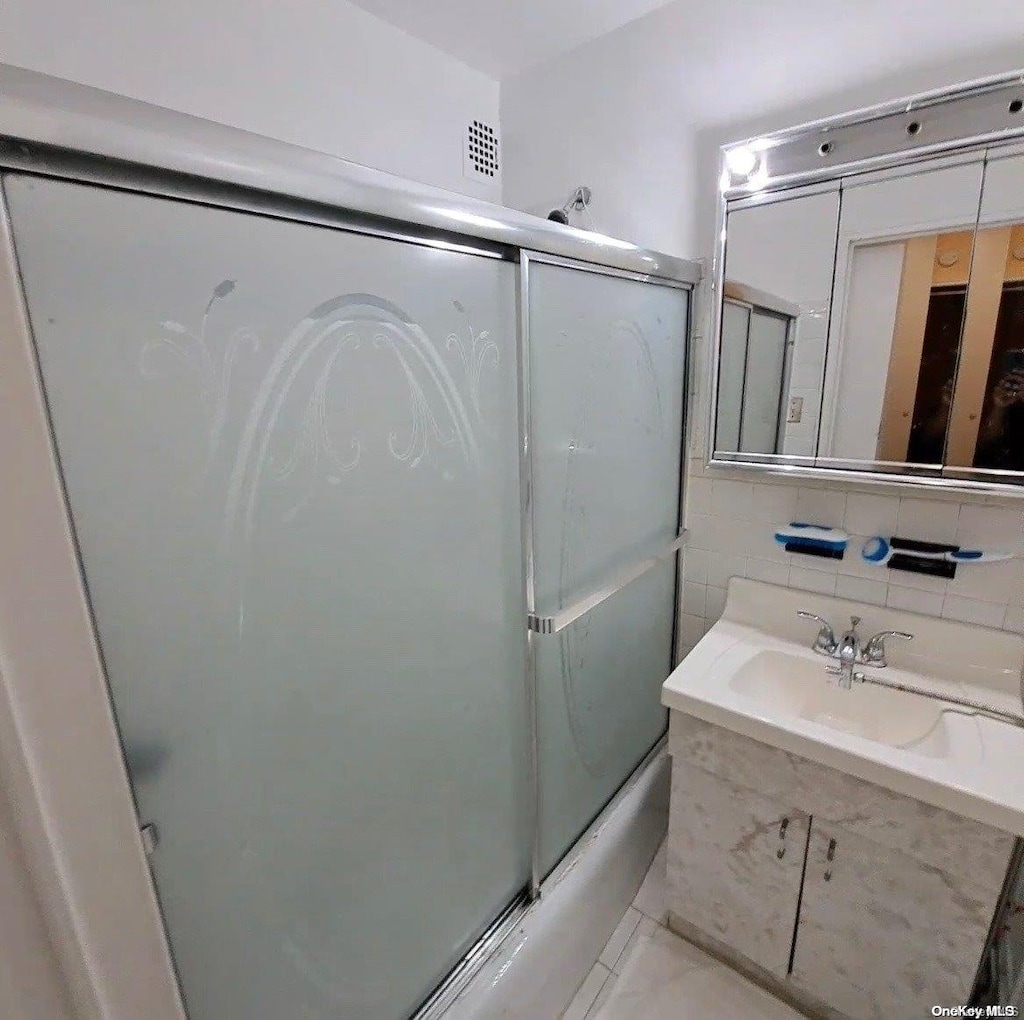 bathroom featuring vanity, backsplash, and enclosed tub / shower combo