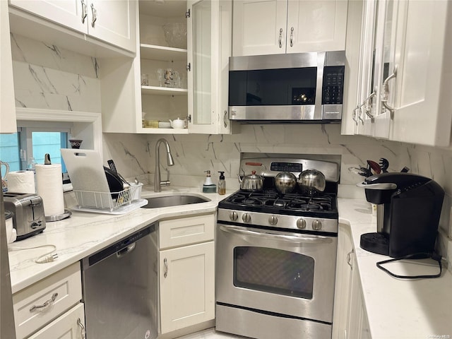 kitchen with white cabinets, sink, light stone countertops, and stainless steel appliances