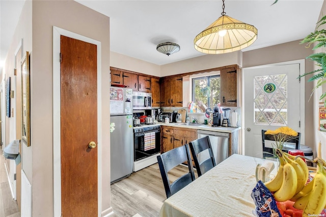 1 Smith St, Glen Head, NY 11545 - kitchen with appliances with stainless steel finishes, light countertops, light wood finished floors, brown cabinets, and pendant lighting