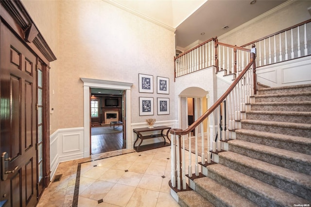 foyer featuring light wood-type flooring, crown molding, and a high ceiling