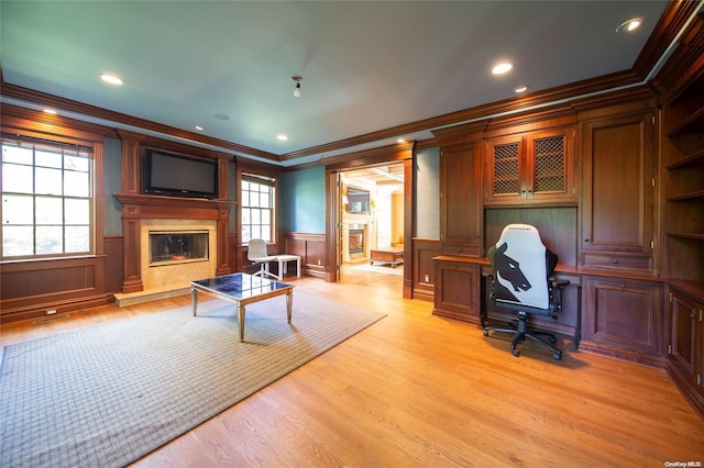 home office featuring plenty of natural light, crown molding, light wood-type flooring, and a fireplace