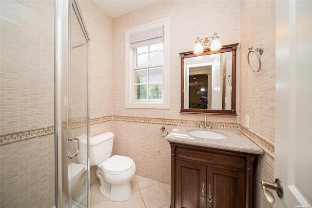 bathroom with tile patterned floors, vanity, tile walls, toilet, and a shower with shower door