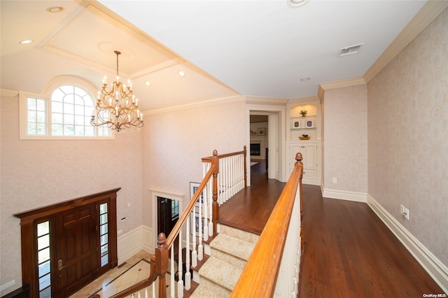 hallway with a chandelier, ornamental molding, and dark wood-type flooring