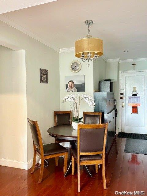 dining room featuring ornamental molding, dark hardwood / wood-style flooring, and a notable chandelier