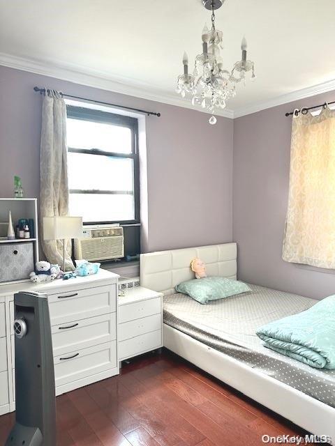 bedroom featuring cooling unit, dark hardwood / wood-style flooring, crown molding, and an inviting chandelier