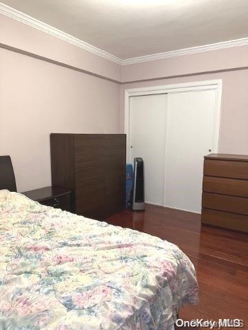 bedroom with dark hardwood / wood-style flooring, a closet, and ornamental molding