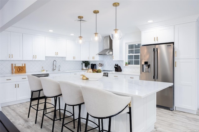 kitchen with sink, wall chimney range hood, stainless steel appliances, and light hardwood / wood-style flooring