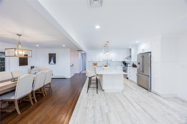 kitchen with white cabinetry, pendant lighting, light wood-type flooring, and appliances with stainless steel finishes