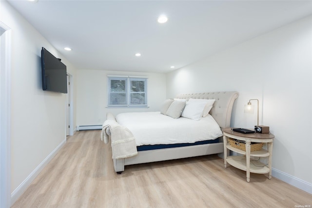 bedroom featuring light wood-type flooring and a baseboard heating unit