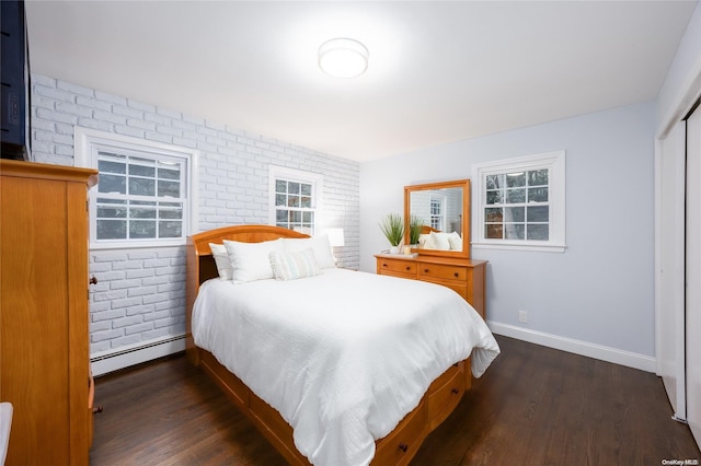 bedroom featuring dark hardwood / wood-style flooring, a baseboard radiator, a closet, and brick wall