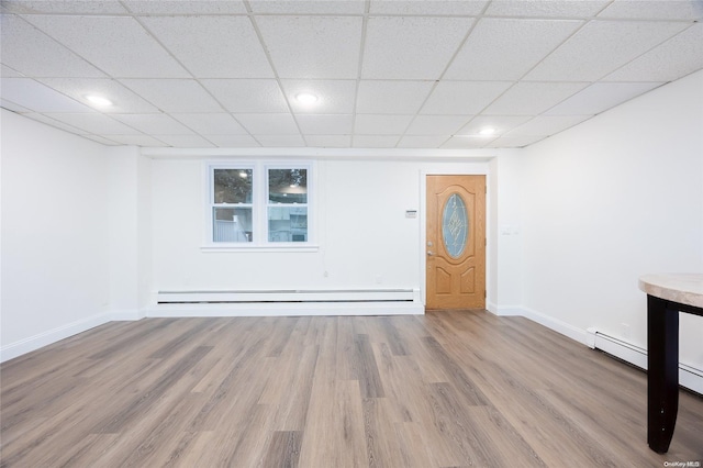 interior space featuring wood-type flooring, a paneled ceiling, and a baseboard radiator