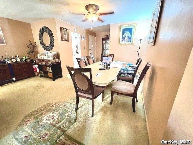 carpeted dining room with ceiling fan