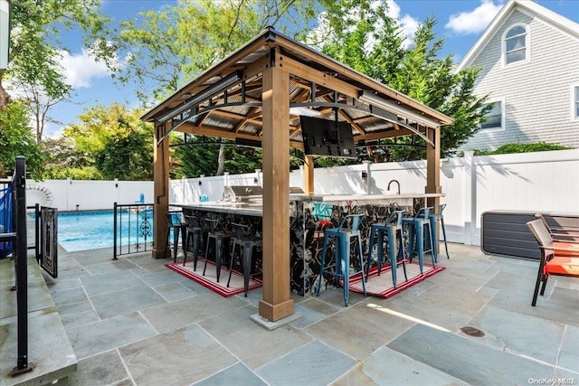 view of patio with a fenced in pool, exterior bar, and a gazebo