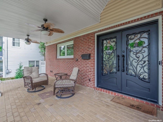 view of exterior entry with ceiling fan, french doors, and covered porch