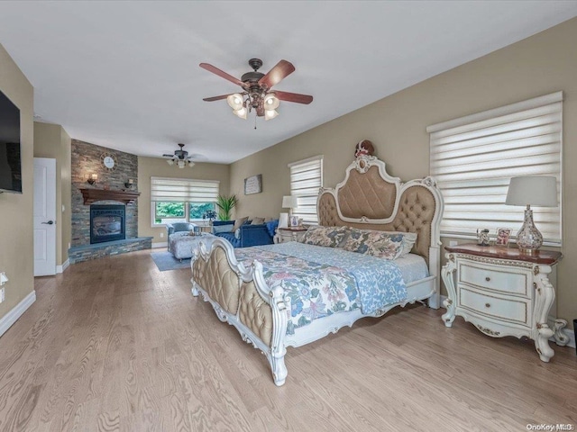 bedroom with ceiling fan, a fireplace, and light wood-type flooring