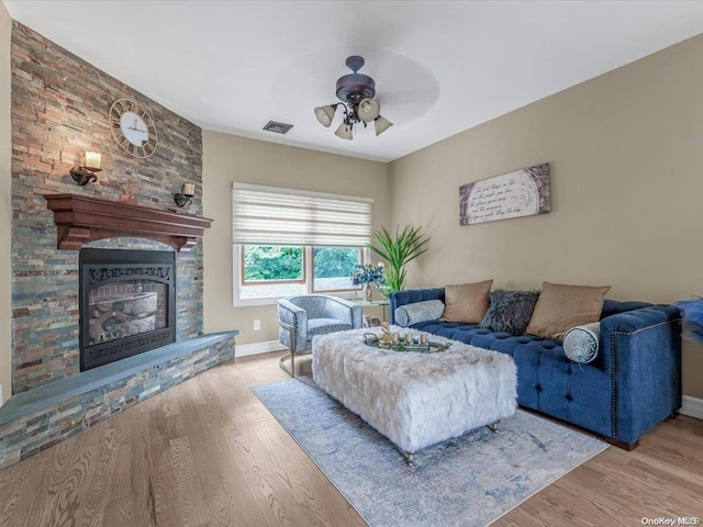 living room featuring a fireplace, ceiling fan, and light hardwood / wood-style flooring