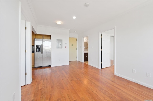 empty room featuring electric panel, crown molding, and light wood-type flooring