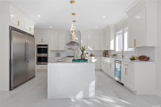 kitchen featuring wall chimney exhaust hood, stainless steel appliances, a kitchen island, pendant lighting, and white cabinets