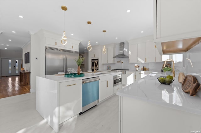 kitchen featuring white cabinetry, stainless steel appliances, wall chimney range hood, pendant lighting, and a kitchen island