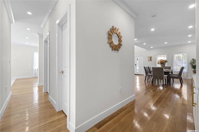 hall with light hardwood / wood-style floors and ornamental molding