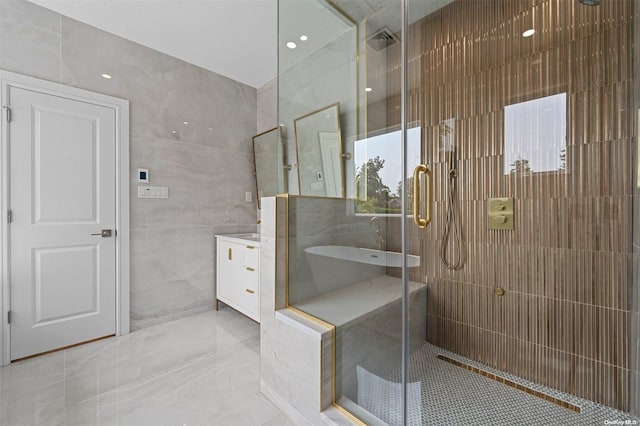 bathroom featuring vanity, a shower with door, and tile walls