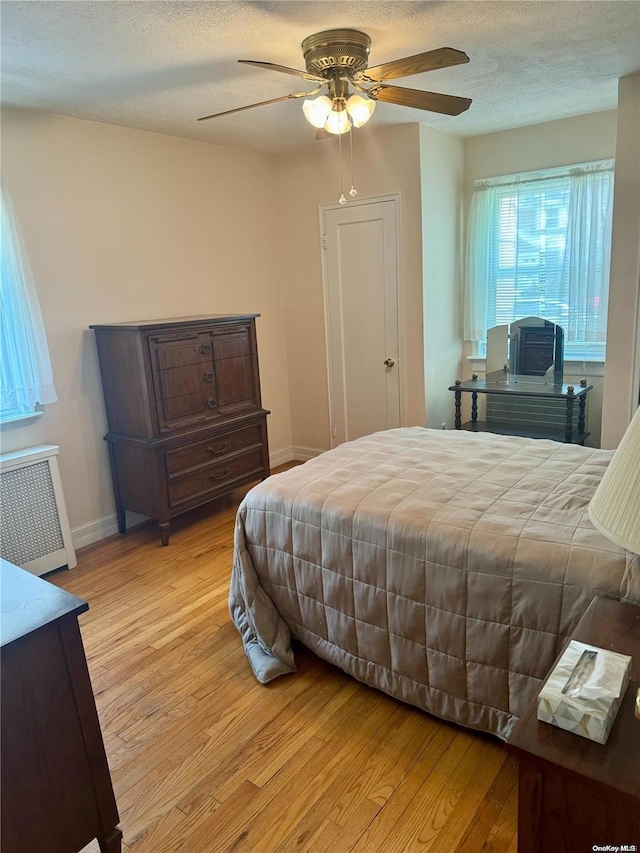 bedroom with radiator, ceiling fan, a textured ceiling, and light wood-type flooring