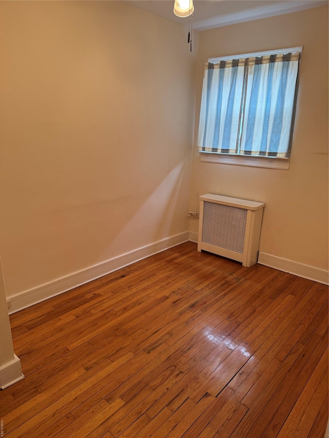 empty room with wood-type flooring and radiator heating unit