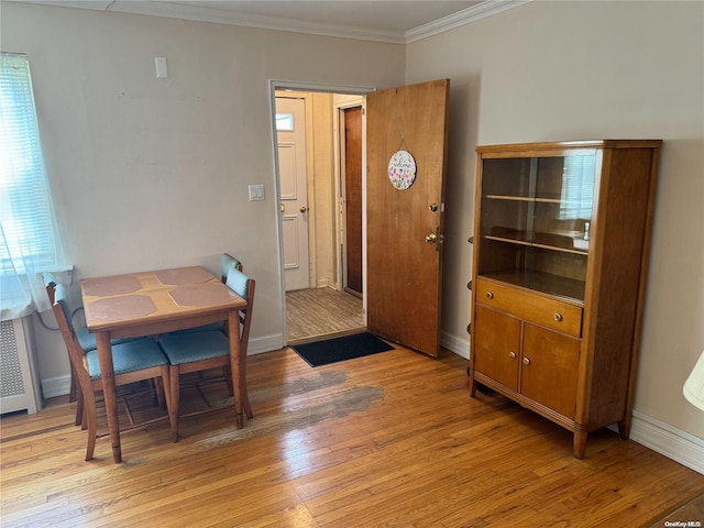 dining area featuring light hardwood / wood-style floors, a healthy amount of sunlight, crown molding, and radiator heating unit