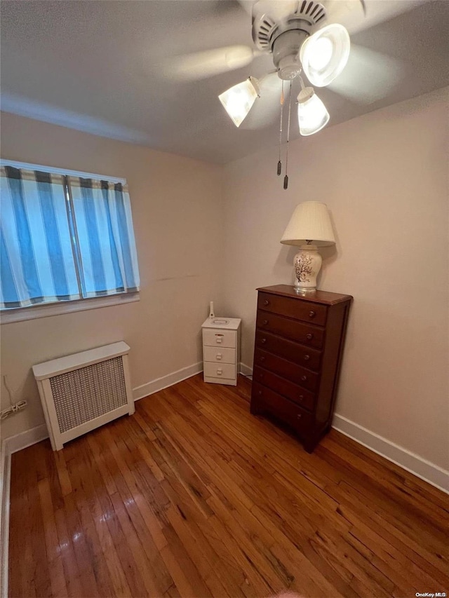 unfurnished bedroom featuring radiator heating unit, ceiling fan, and wood-type flooring