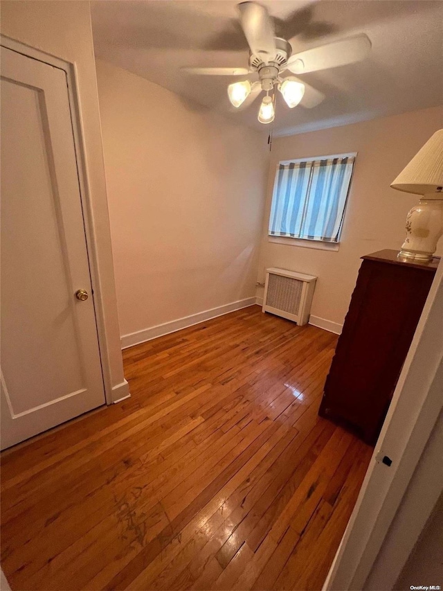 unfurnished bedroom with hardwood / wood-style flooring, ceiling fan, and radiator heating unit