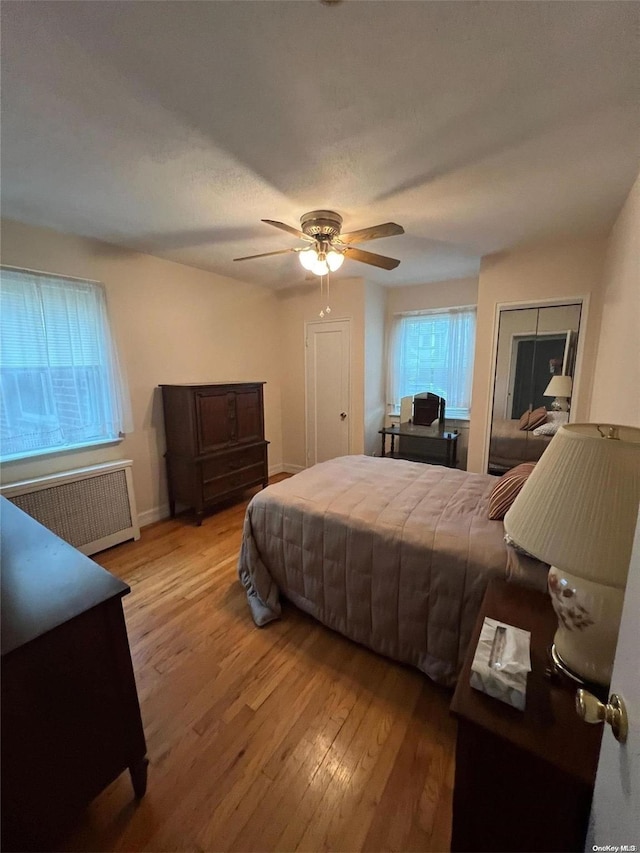 bedroom with ceiling fan, radiator heating unit, and light hardwood / wood-style floors