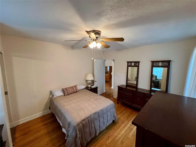 bedroom with a textured ceiling, hardwood / wood-style flooring, and ceiling fan