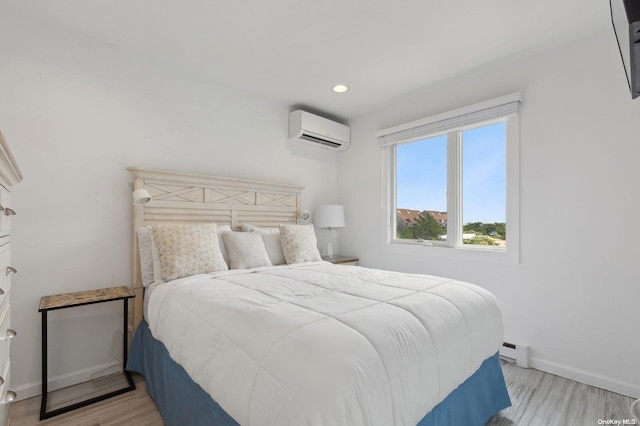 bedroom featuring a wall mounted air conditioner, light wood-type flooring, and a baseboard heating unit