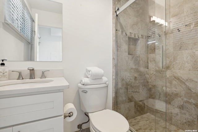 bathroom with a shower with door, vanity, and toilet