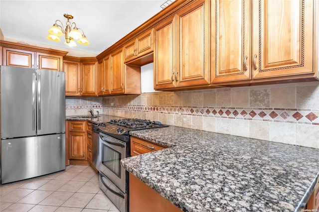 kitchen with hanging light fixtures, stainless steel appliances, an inviting chandelier, dark stone counters, and decorative backsplash