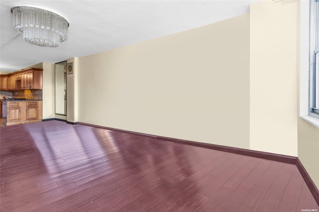 unfurnished living room featuring an inviting chandelier and hardwood / wood-style flooring